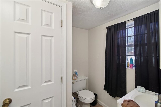 bathroom featuring a sink, a textured ceiling, and toilet