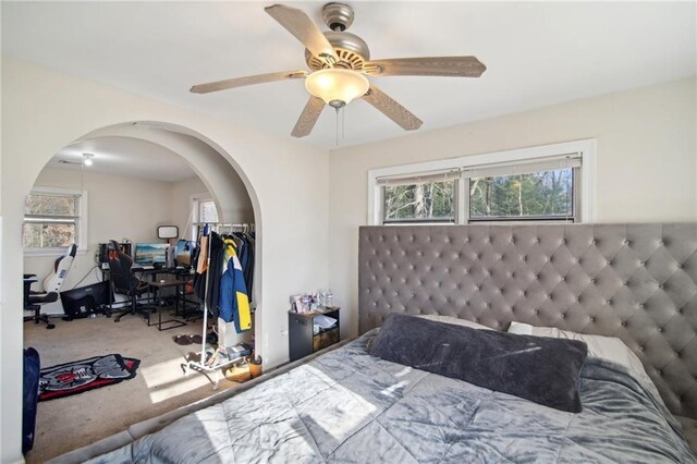 bedroom with carpet floors, arched walkways, and ceiling fan