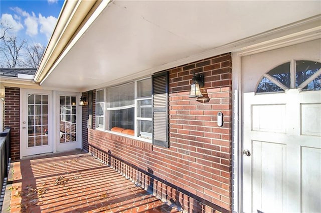 property entrance featuring covered porch and brick siding