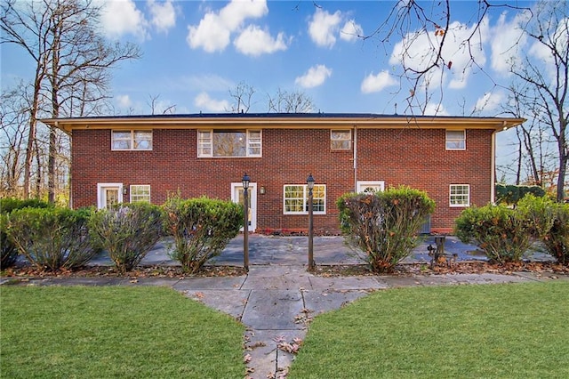 exterior space featuring brick siding and a front yard