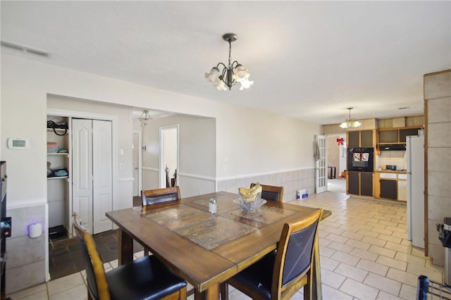 dining room with wainscoting, visible vents, and an inviting chandelier