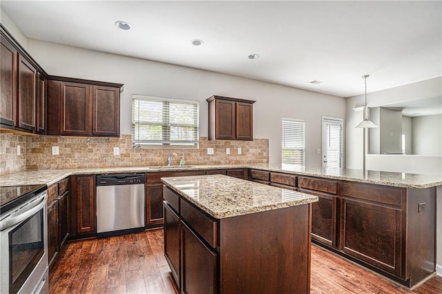 kitchen featuring a wealth of natural light, appliances with stainless steel finishes, dark wood-type flooring, and a center island