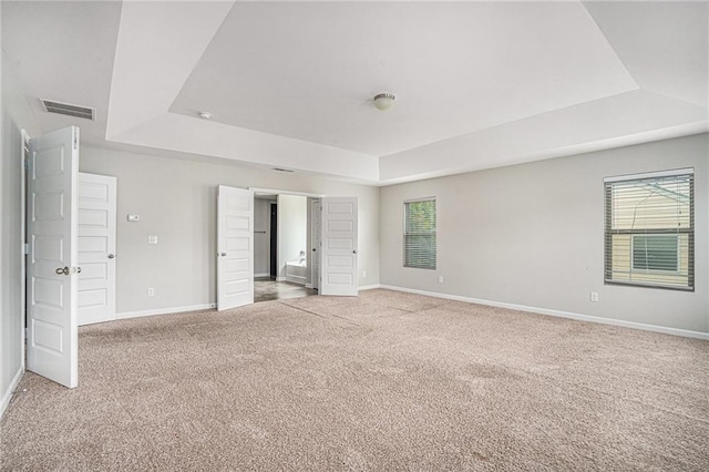 unfurnished bedroom with light carpet and a raised ceiling