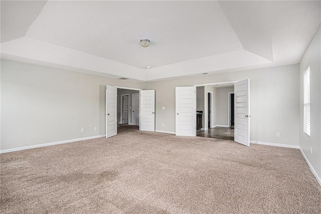 unfurnished bedroom with carpet flooring and a tray ceiling