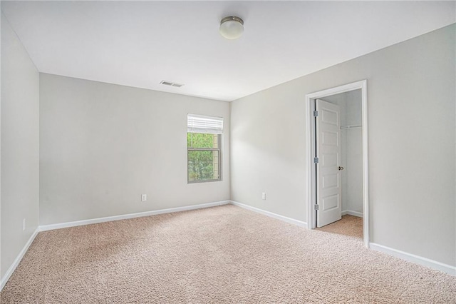 unfurnished bedroom with light colored carpet, a closet, and a walk in closet