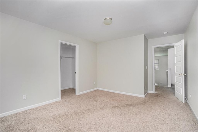 unfurnished bedroom featuring a spacious closet, light carpet, and a closet