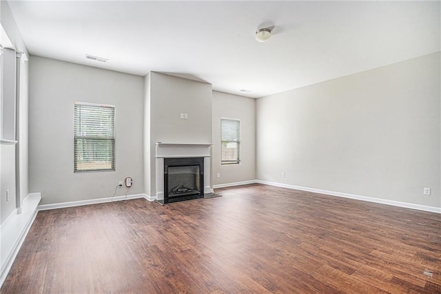 unfurnished living room featuring dark hardwood / wood-style floors and a healthy amount of sunlight