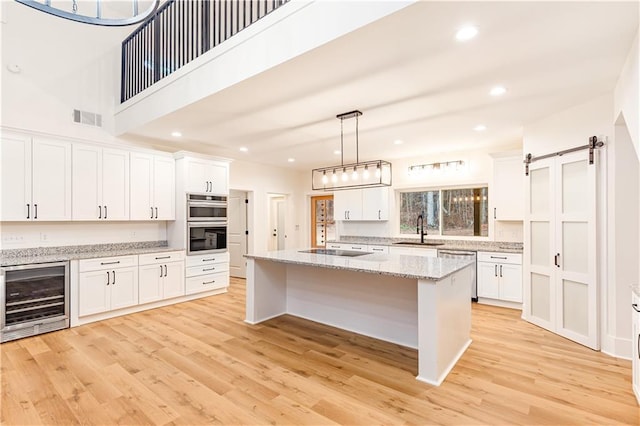 kitchen with wine cooler, a barn door, a center island, and white cabinets