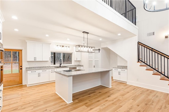 kitchen featuring white cabinetry, decorative light fixtures, sink, and a kitchen island