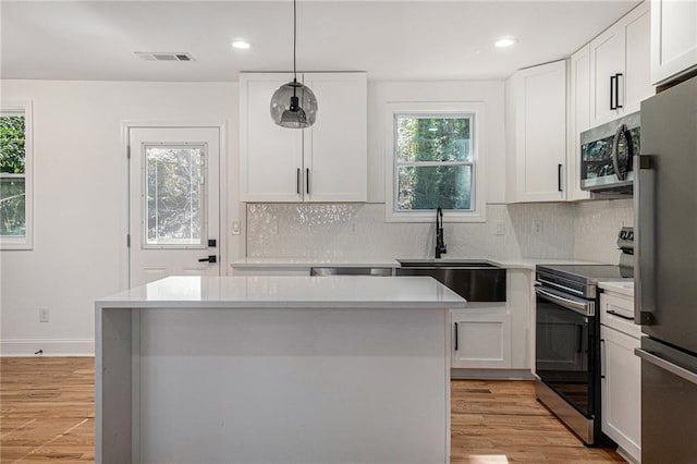 kitchen featuring pendant lighting, white cabinetry, appliances with stainless steel finishes, and sink