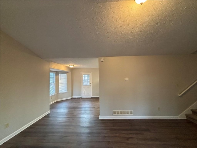 empty room featuring dark wood-type flooring and a textured ceiling