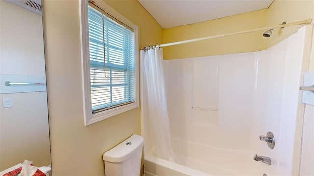 bathroom with toilet, a healthy amount of sunlight, and shower / bathtub combination with curtain