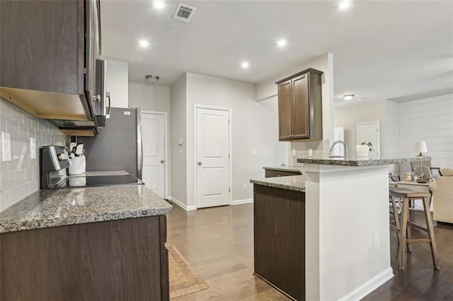 kitchen with stone countertops, range, a kitchen breakfast bar, and kitchen peninsula