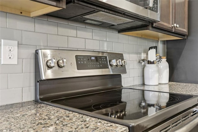 kitchen featuring stainless steel range with electric cooktop, light stone counters, and decorative backsplash