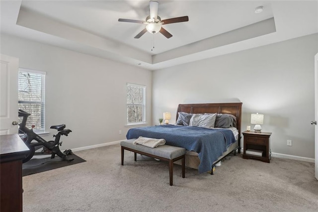 bedroom with ceiling fan, a tray ceiling, and light carpet