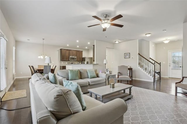 living room featuring dark wood-type flooring and ceiling fan with notable chandelier