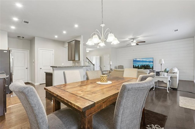 dining space featuring dark wood-type flooring and ceiling fan with notable chandelier