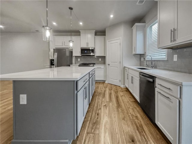 kitchen with tasteful backsplash, a center island, sink, white cabinetry, and stainless steel appliances