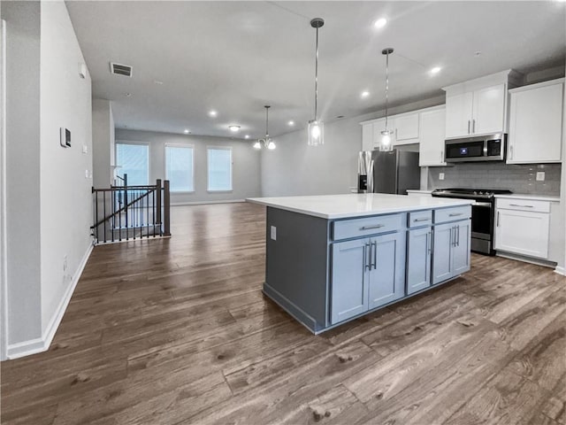 kitchen with hanging light fixtures, white cabinets, stainless steel appliances, and a kitchen island