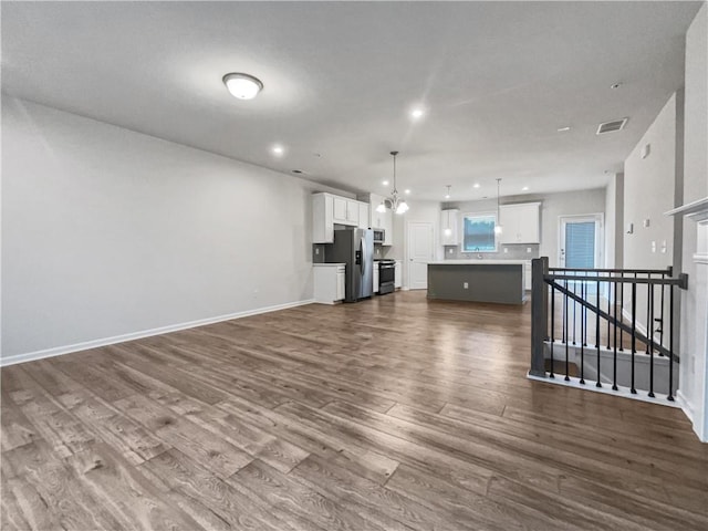 unfurnished living room with sink, dark hardwood / wood-style floors, and a chandelier