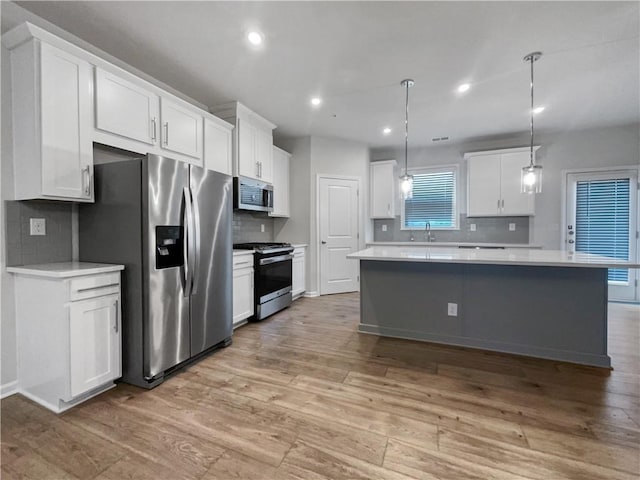 kitchen featuring stainless steel appliances, pendant lighting, white cabinets, and tasteful backsplash