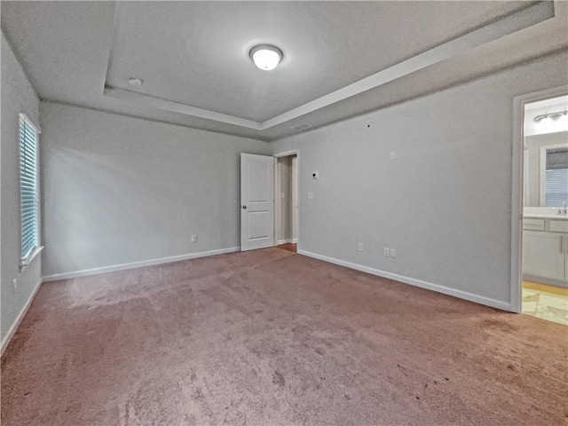 empty room with a tray ceiling and carpet flooring