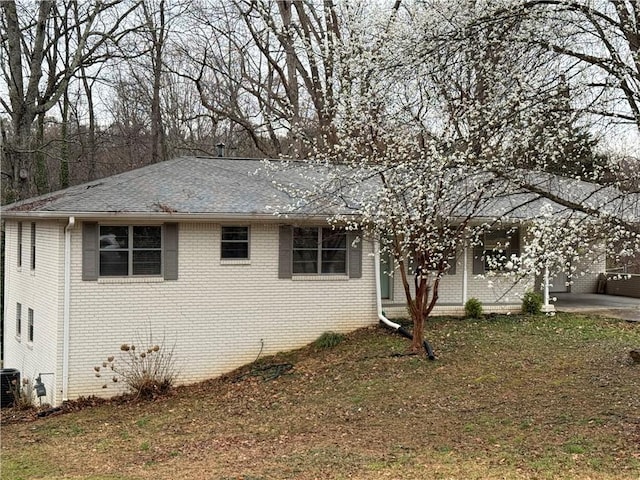 view of front of house featuring brick siding, central AC, and a shingled roof