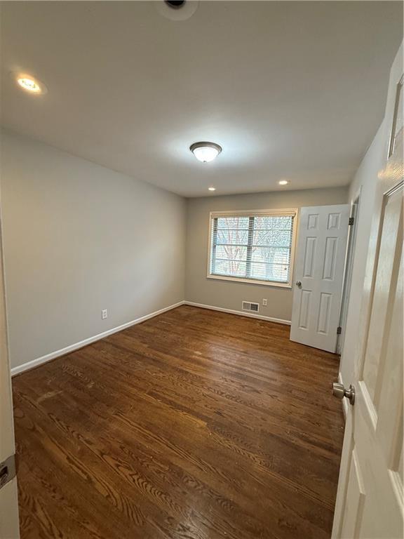 unfurnished room with recessed lighting, visible vents, baseboards, and dark wood-style flooring