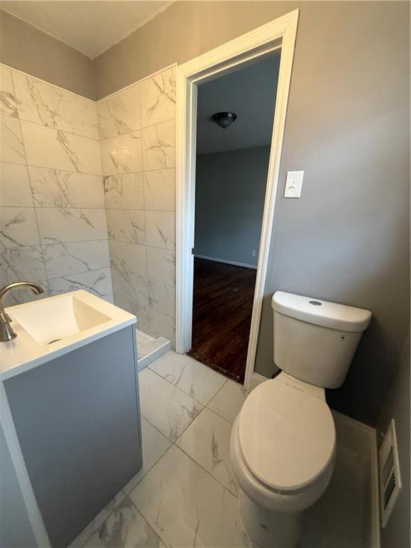 full bathroom with vanity, toilet, marble finish floor, and a tile shower