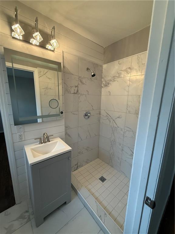 bathroom with tasteful backsplash, marble finish floor, a shower stall, and vanity