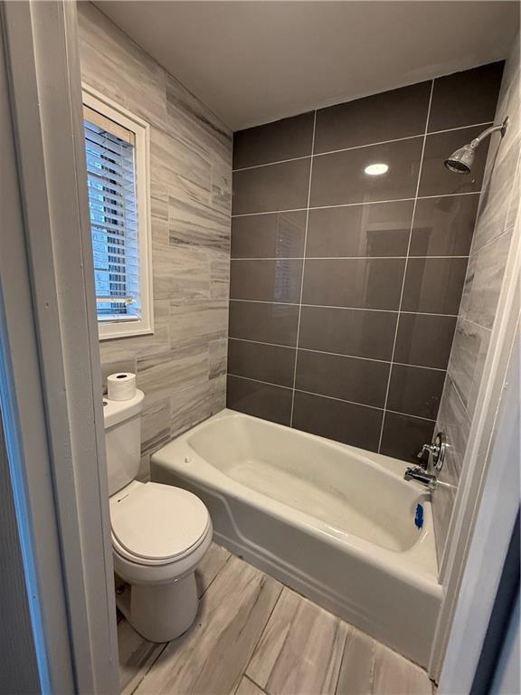 full bathroom featuring wood finished floors, toilet, and shower / washtub combination