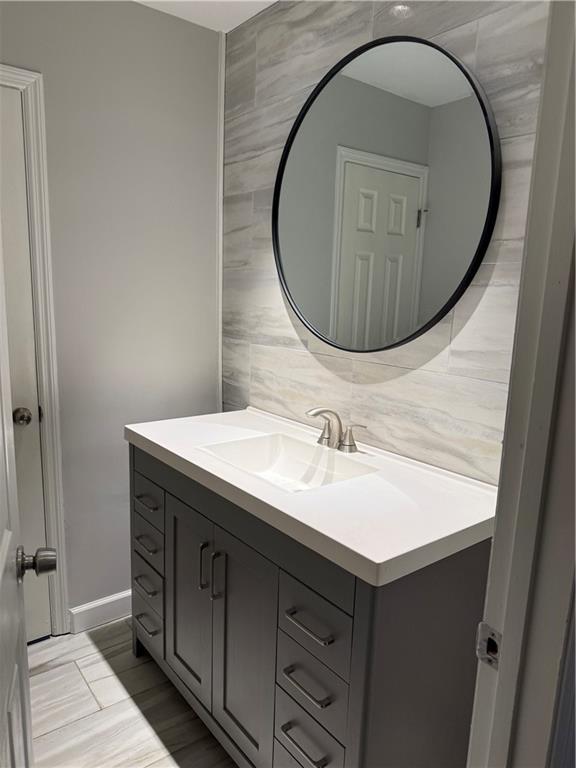 bathroom with vanity, tile walls, baseboards, and tasteful backsplash