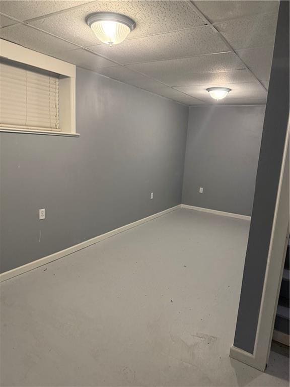 spare room featuring concrete floors, baseboards, and a drop ceiling