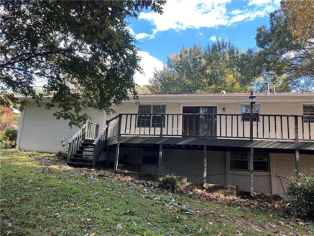 rear view of property with a lawn, a deck, stairs, and brick siding