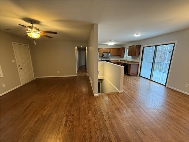 kitchen with baseboards, open floor plan, appliances with stainless steel finishes, and dark wood-type flooring