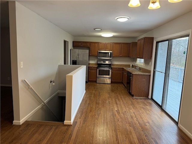 kitchen with a sink, stainless steel appliances, baseboards, and dark wood finished floors