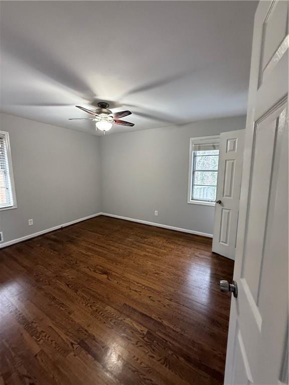 unfurnished room featuring baseboards, ceiling fan, and dark wood finished floors