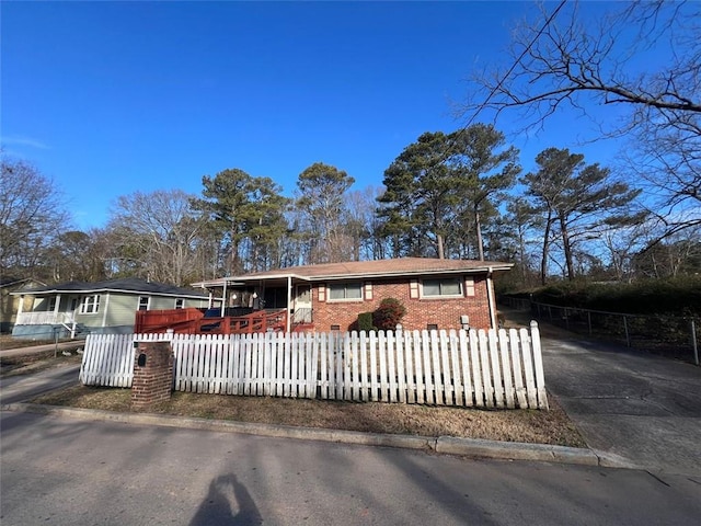 ranch-style house with a fenced front yard, concrete driveway, and brick siding