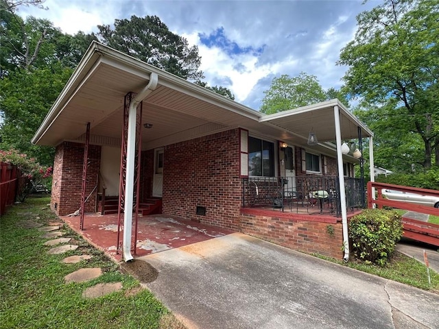 view of side of property with an attached carport, driveway, crawl space, and brick siding