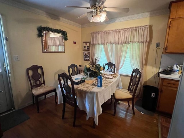 dining area with dark wood-type flooring, a ceiling fan, and ornamental molding