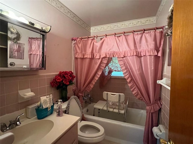 full bath featuring tile walls, toilet, a wainscoted wall, shower / bath combination with curtain, and vanity