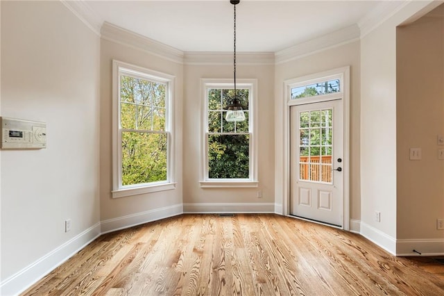 unfurnished dining area featuring light hardwood / wood-style floors, ornamental molding, and a wealth of natural light