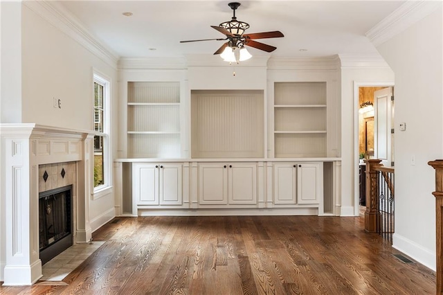 unfurnished living room featuring ceiling fan, a healthy amount of sunlight, dark hardwood / wood-style flooring, and a tile fireplace