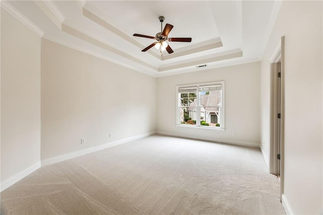 carpeted spare room with a tray ceiling, ceiling fan, and ornamental molding