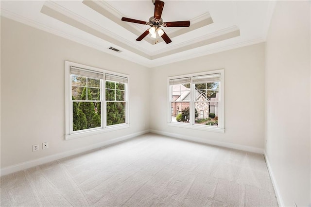 carpeted empty room featuring a raised ceiling, ceiling fan, and crown molding