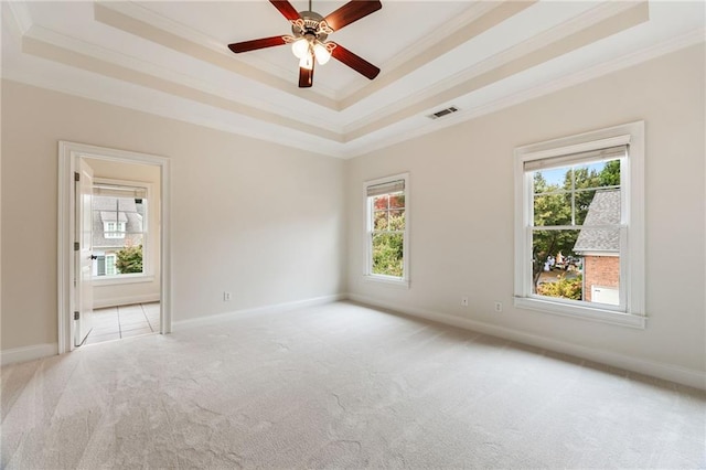 unfurnished room with a tray ceiling, ceiling fan, light carpet, and ornamental molding