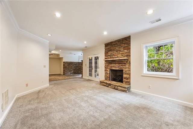 unfurnished living room with a fireplace, french doors, light colored carpet, and crown molding