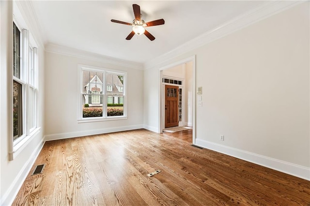 empty room featuring ceiling fan, wood-type flooring, a healthy amount of sunlight, and ornamental molding