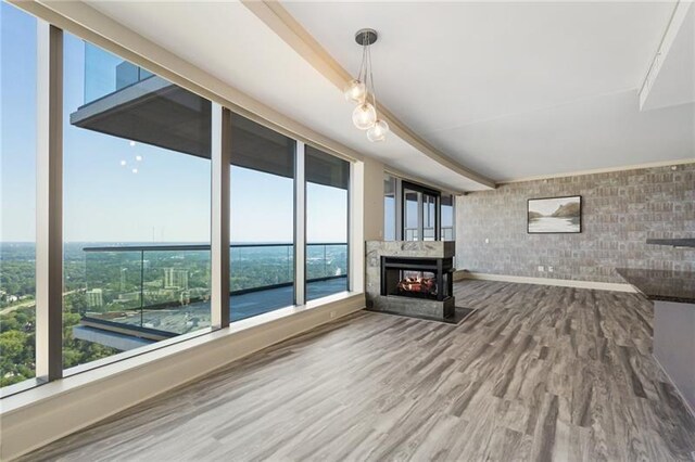 unfurnished living room with a healthy amount of sunlight, a multi sided fireplace, and wood-type flooring