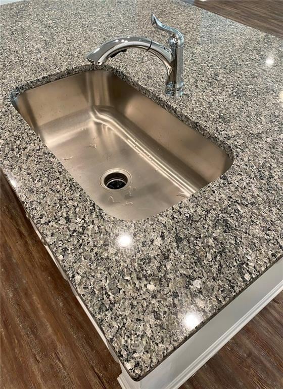 details with sink, stone counters, and dark hardwood / wood-style floors